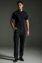 Man wearing the TECHTEE black polo shirt and pants against a gray background