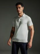 Man wearing the TECHTEE light gray polo shirt against a dark background